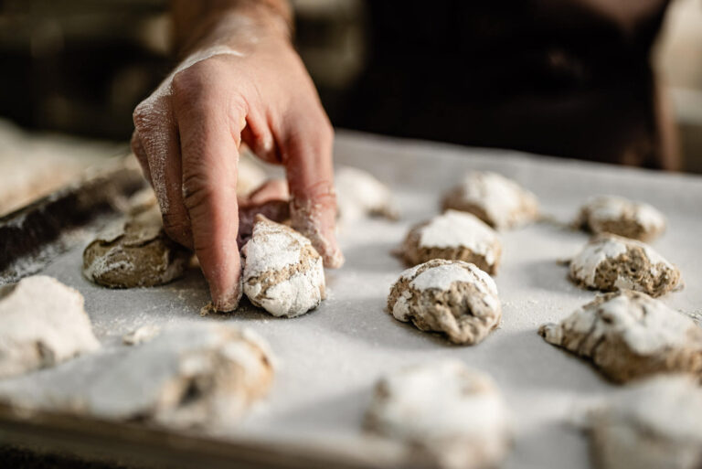 Hand platziert mit Puderzucker best&auml;ubte Teiglinge auf Backblech mit Backpapier