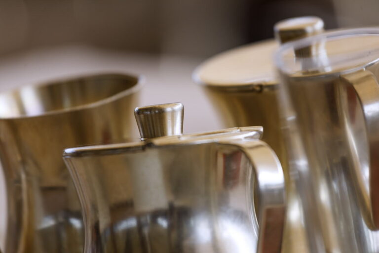 Nahaufnahme mehrerer silberner Metallk&auml;nnchen auf Tablett, Vordergrund scharf, Hintergrund unscharf