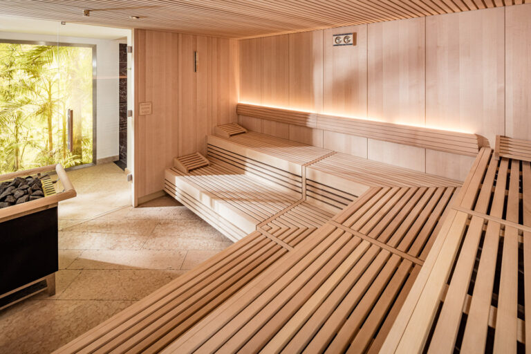 Hotel-Sauna mit mehrstufigen Holzliegen, Holzverkleidung, indirekter LED-Beleuchtung und Glast&uuml;r